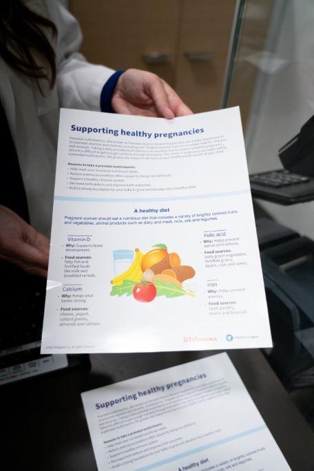 A person holding a flyer "Supporting healthy pregnancies"