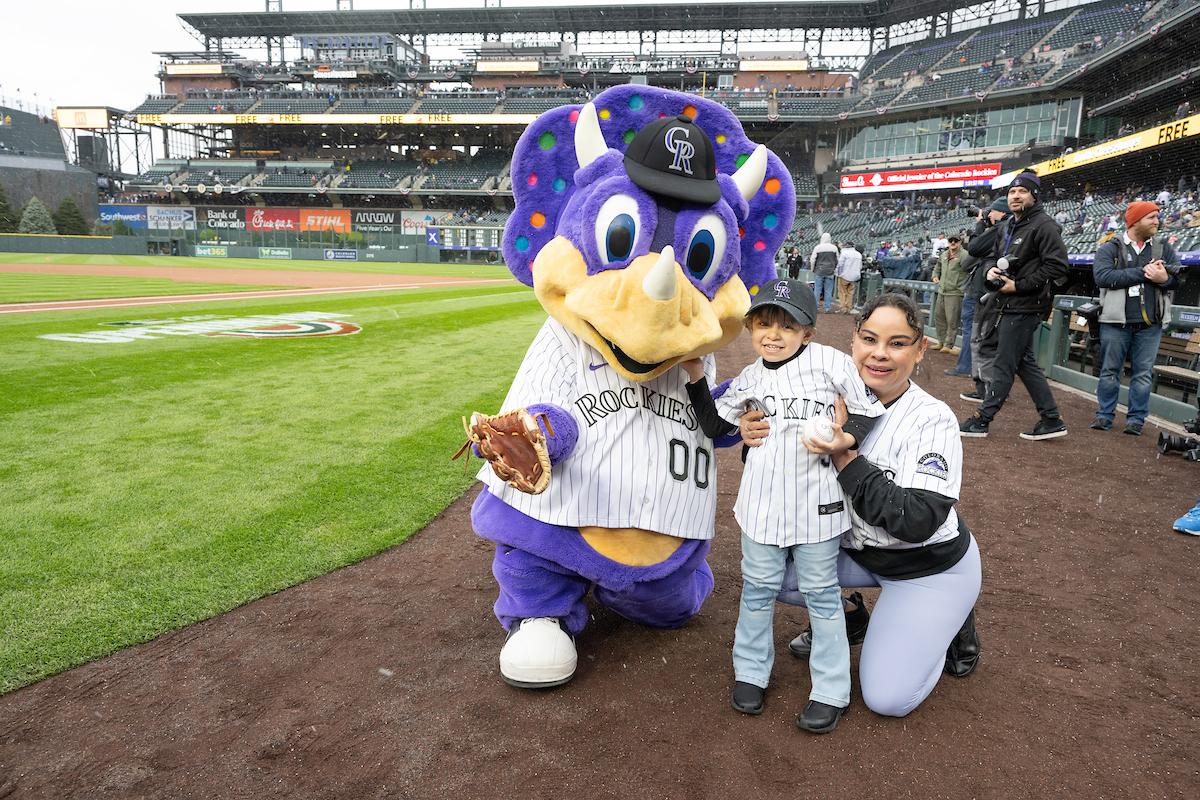 Colorado Rockies mascot with a child and adult on a baseball field