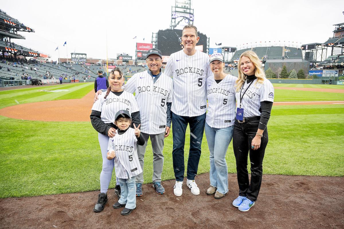 A group of people in Rockies shirts on a baseball field posing for the camera