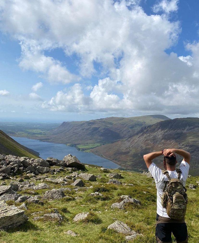 A person looking out at a vast hilly, wilderness area.