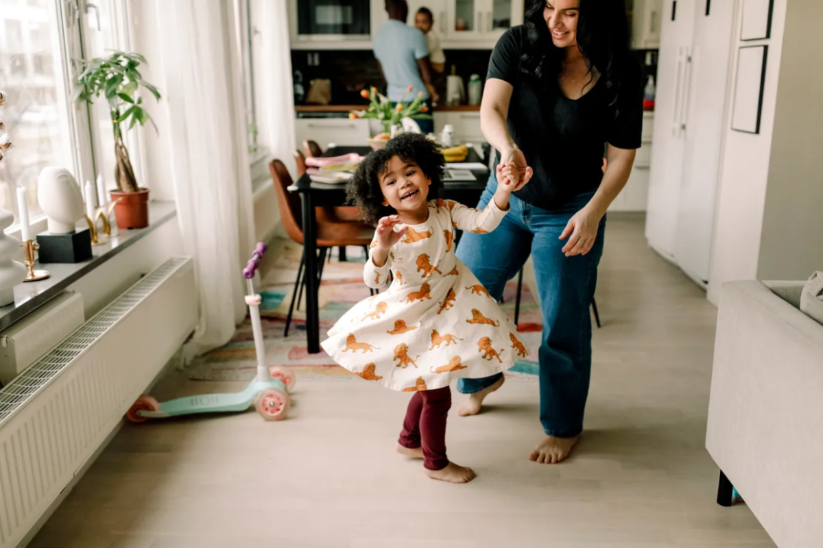 Parent twirling a little child around their dinning room