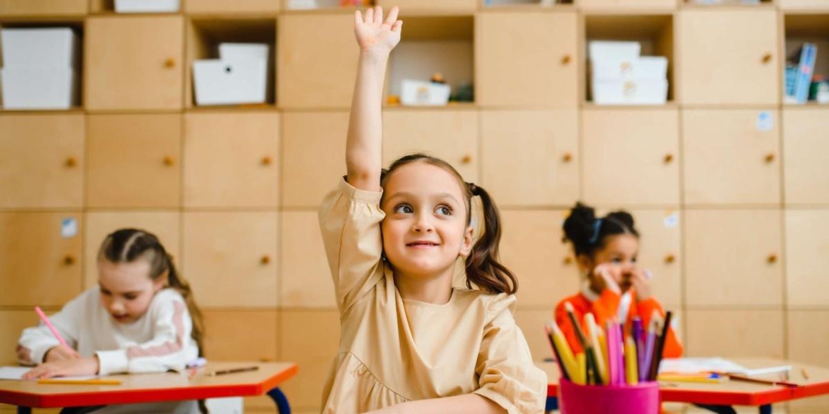 Student raising her hand in a classroom. 