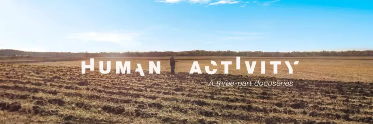 In white broken letters "Human activity". A person standing in a bare crop field, a blue sky above.