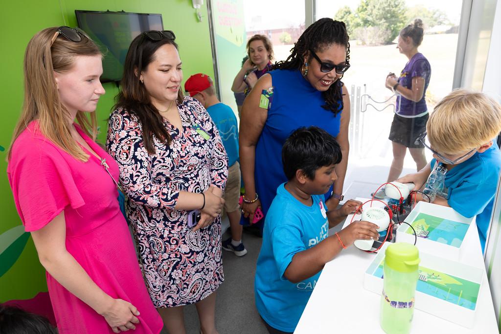 Two students and three adults conduct an experiment inside of the Curiosity Cube.