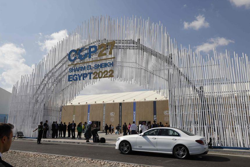 People walking in front of COP27 arch