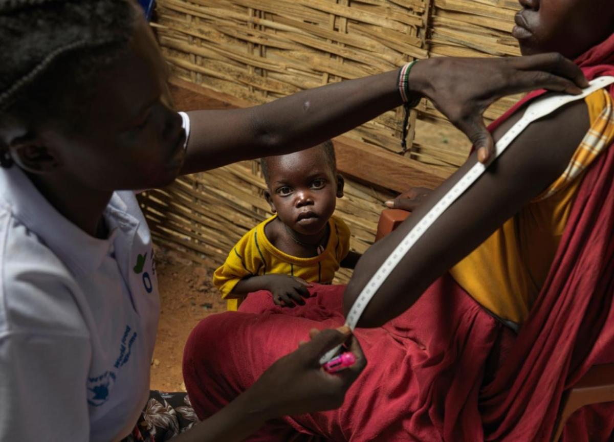 Adheet Akeen Alhia, 20, and her child are screened for malnutrition by Action Against Hunger staff after arriving at the South Sudan border point in Majok Yinthiou.  