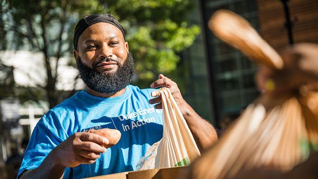 A volunteer packing a bag with food outside.