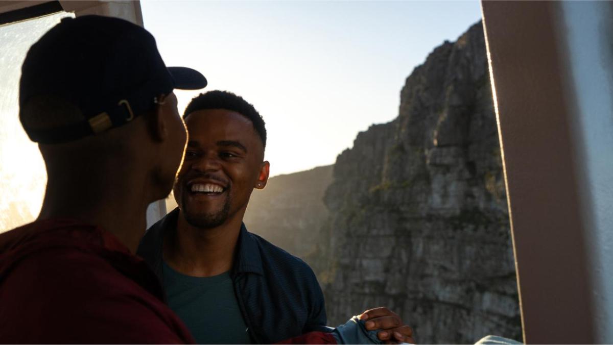 Two people looking at each other. A rocky landscape behind them.