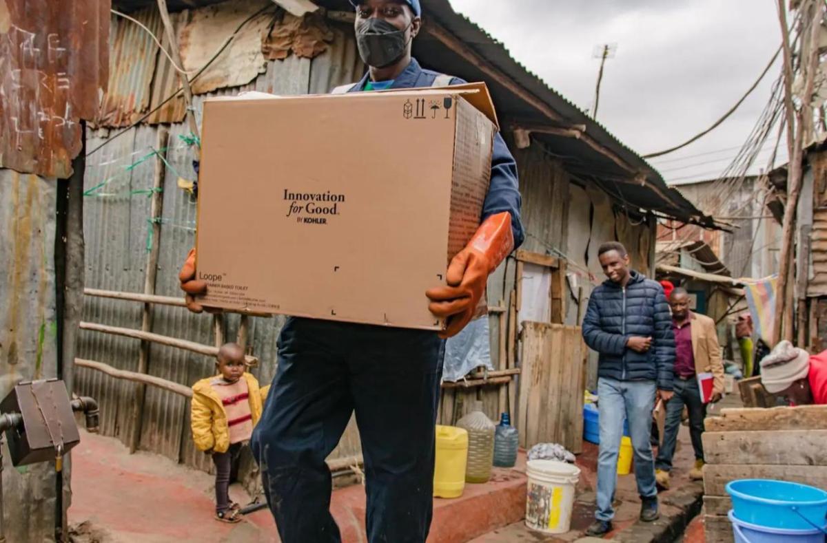 A person in protective gear holding a box in a residential area.