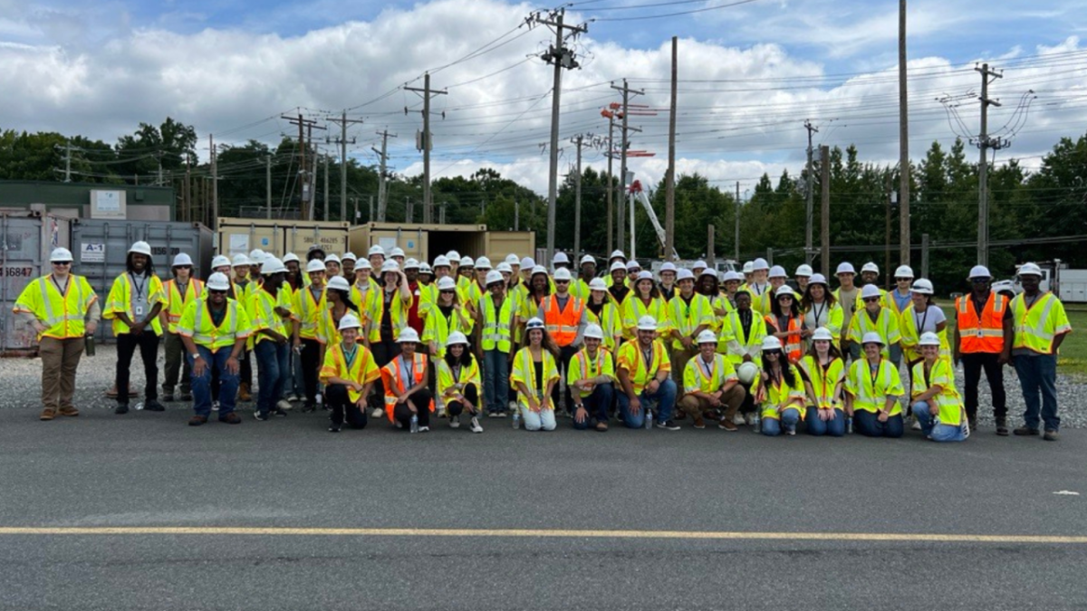 A group on high-vis vests and hard hats posed outside.