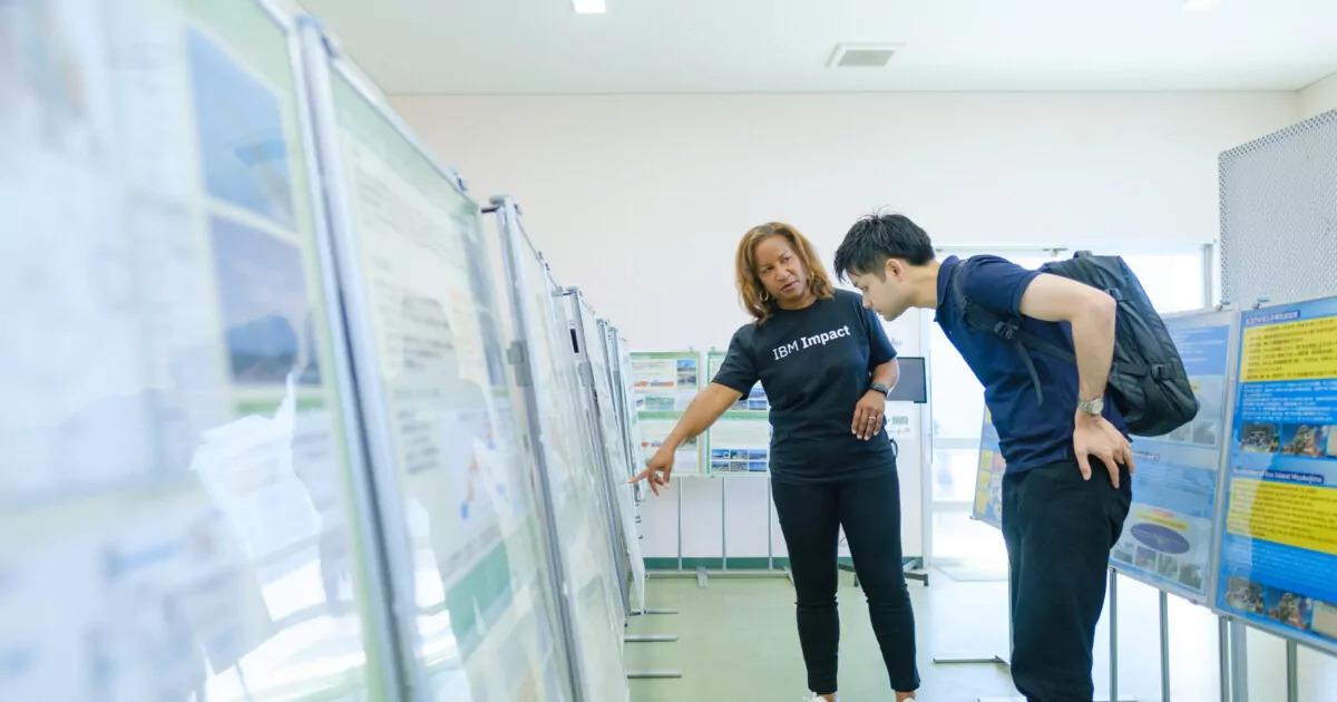 Takahito Motonaga and another looking at rows of boards set up in a room.