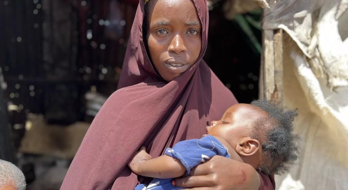 Woman looks at camera while holding baby