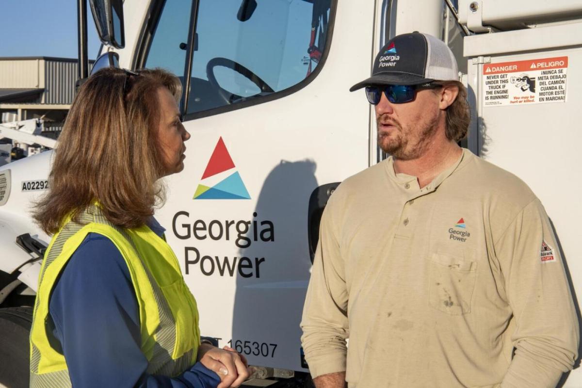 Two people talking next to a Georgia Power truck.