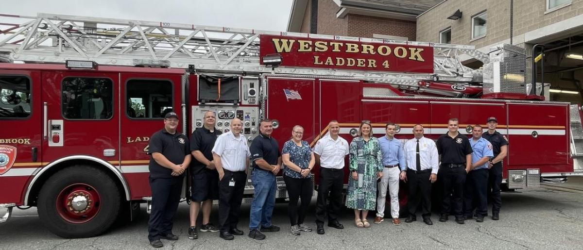 A group posed in front of a fire truck outside.