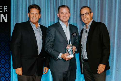 Three people stood next to each other holding an award, in front of a blue backdrop  