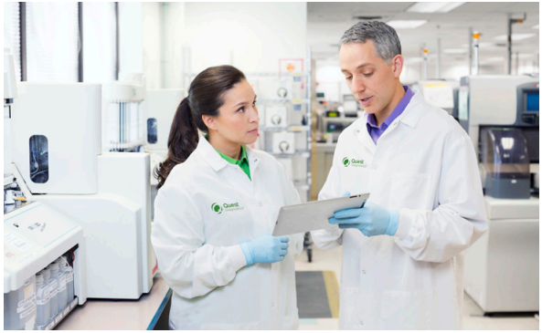 Two people in lab coats talking.