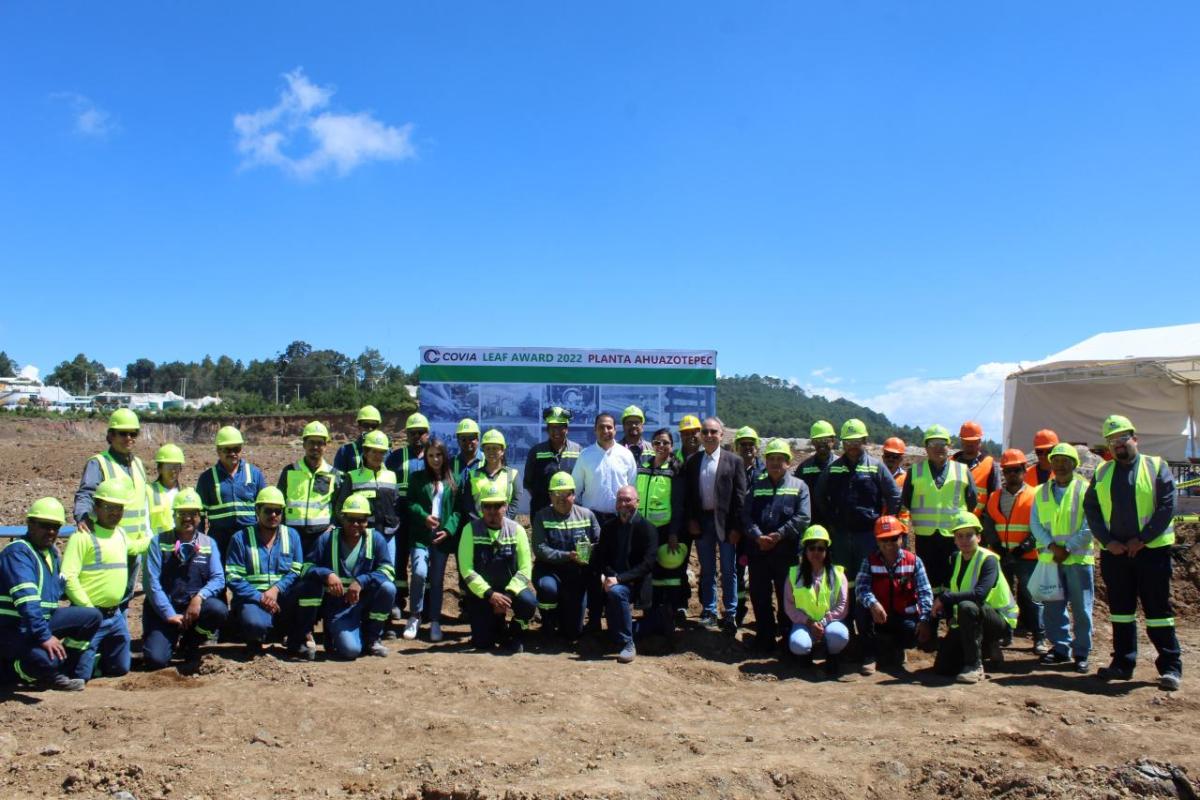 A large group posed outside. Each in high-vis vest and hard hats.