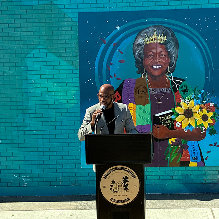 Someone speaking at a podium in front of a large mural