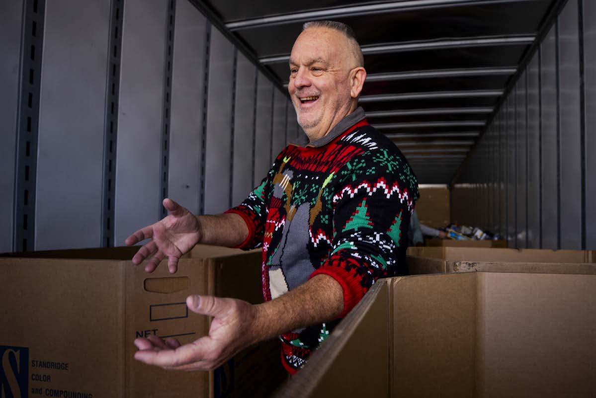 A smiling person loading boxes in a semi trailer.