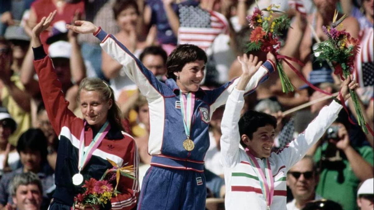 Three medalists waving to an audience 