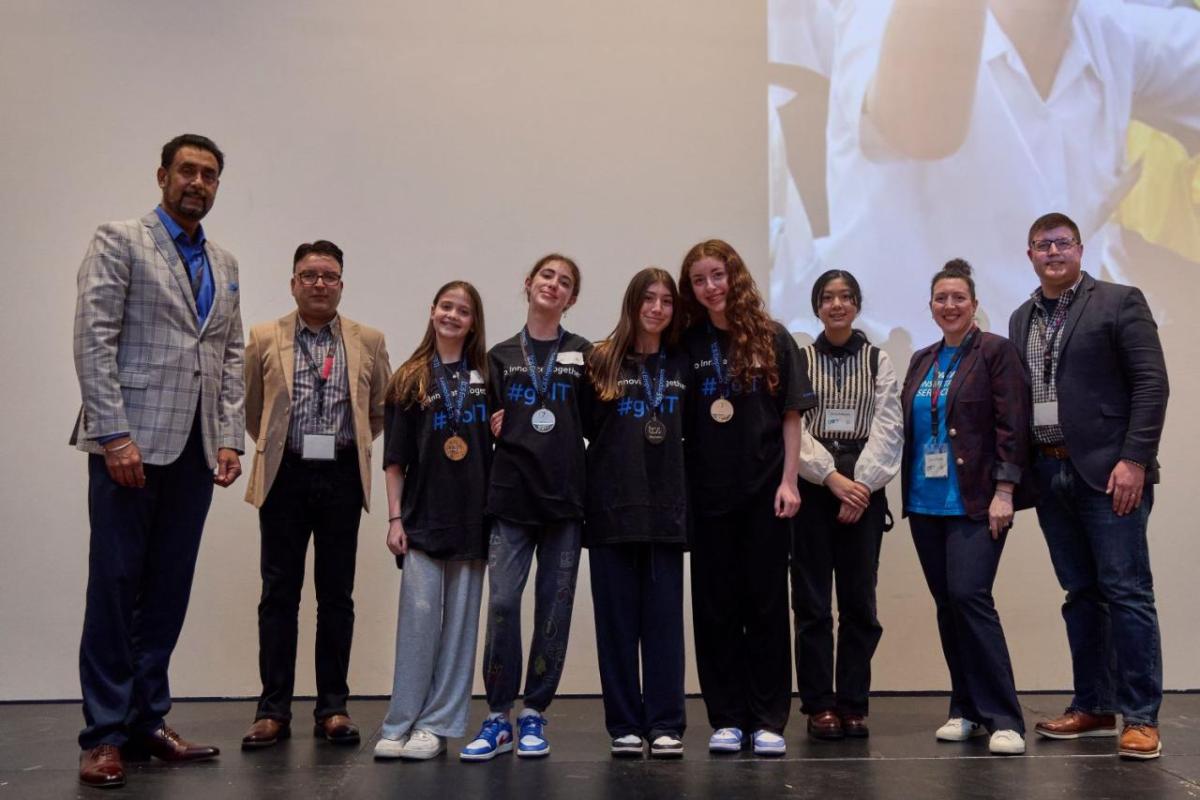 A group of students and presenters on a stage.