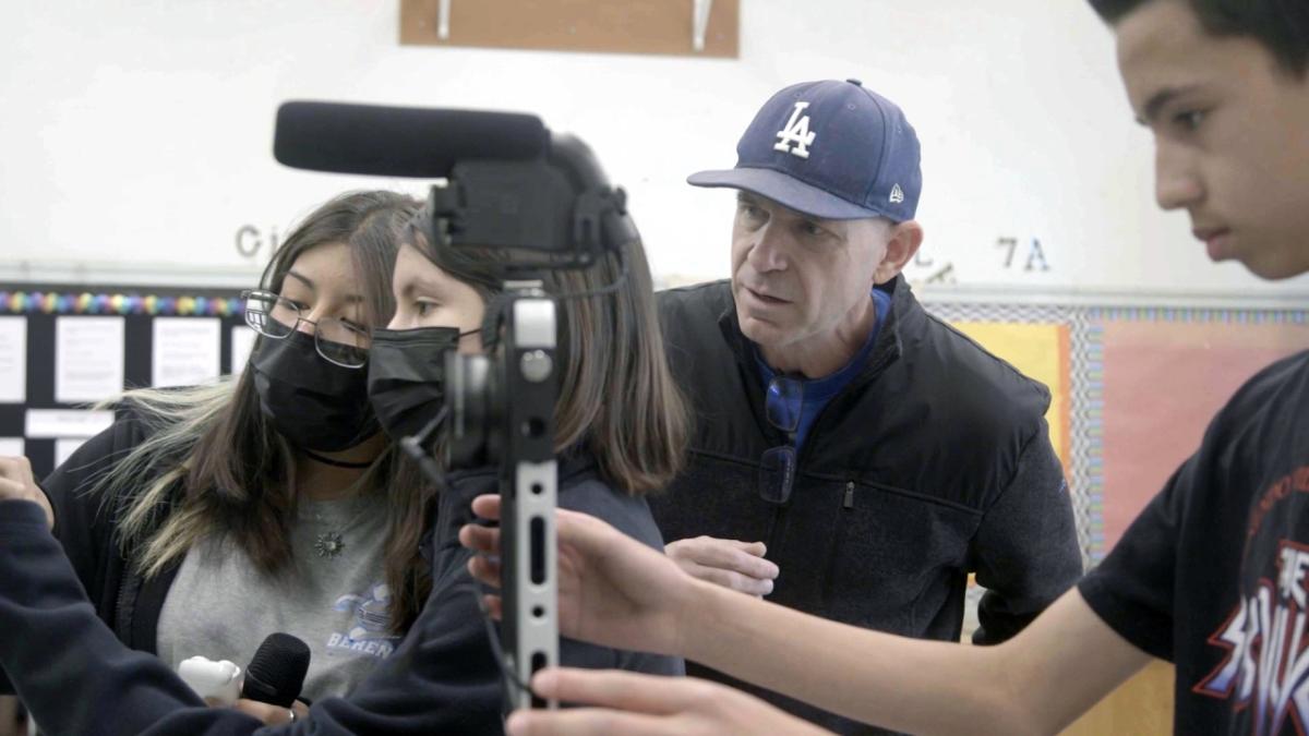 A teacher assisting students with A/V equipment