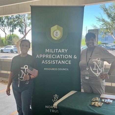 Two people posed by a banner "Military Appreciation & Assistance."