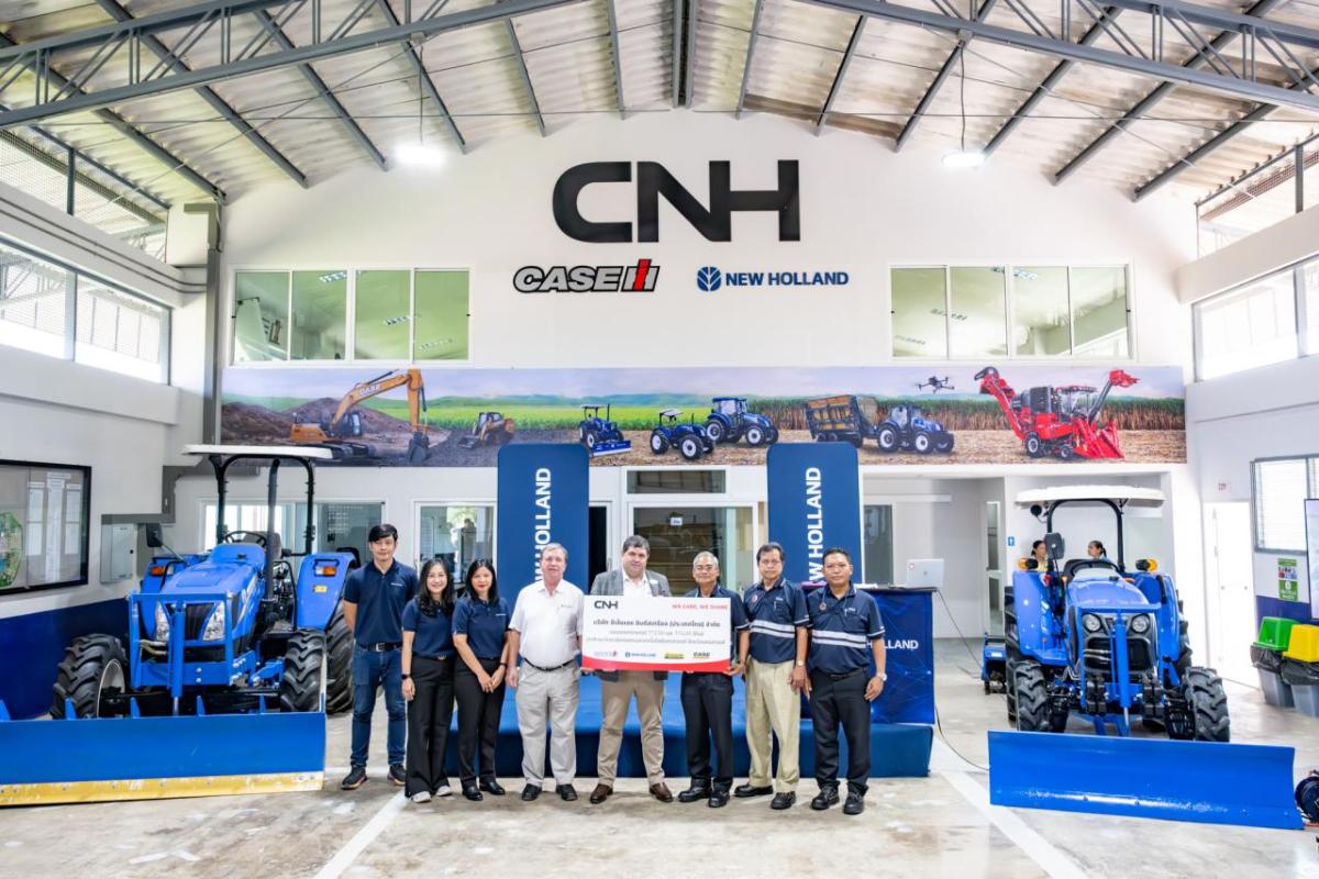 A group posed, some holding a large check, in a CNH showroom.