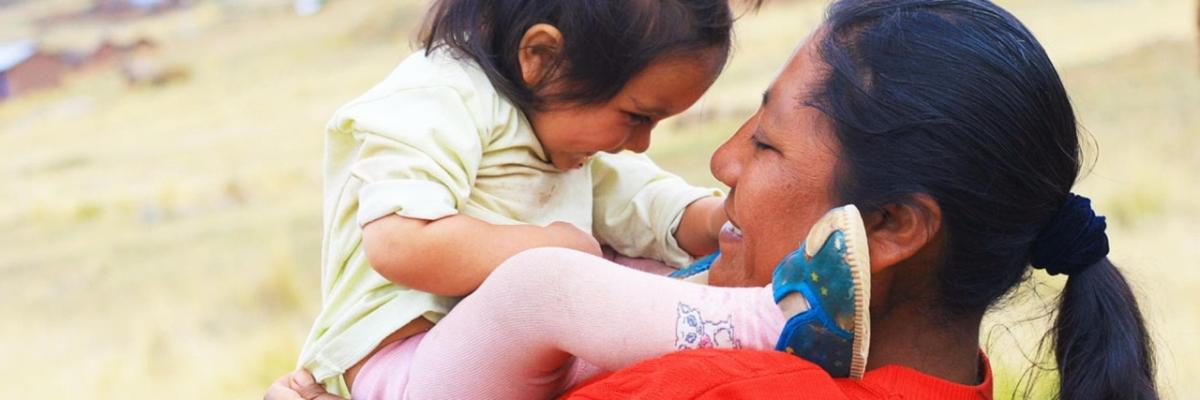 Adult holding a small child close to them, face to face