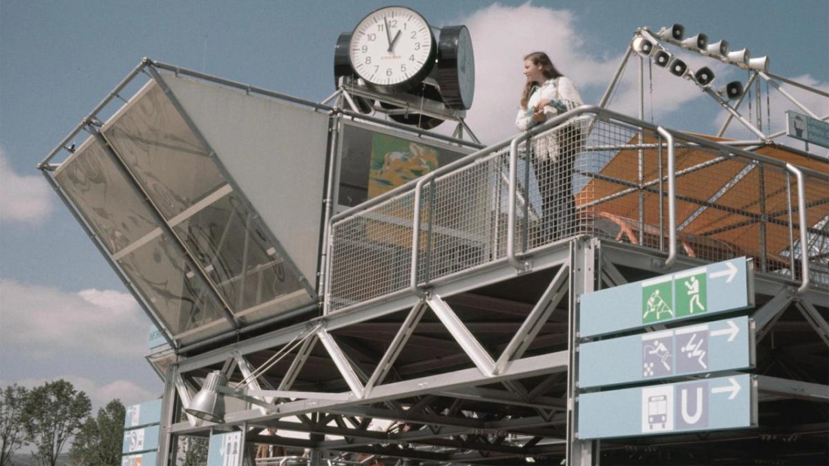 a person in spectator stands, picture based signage below them