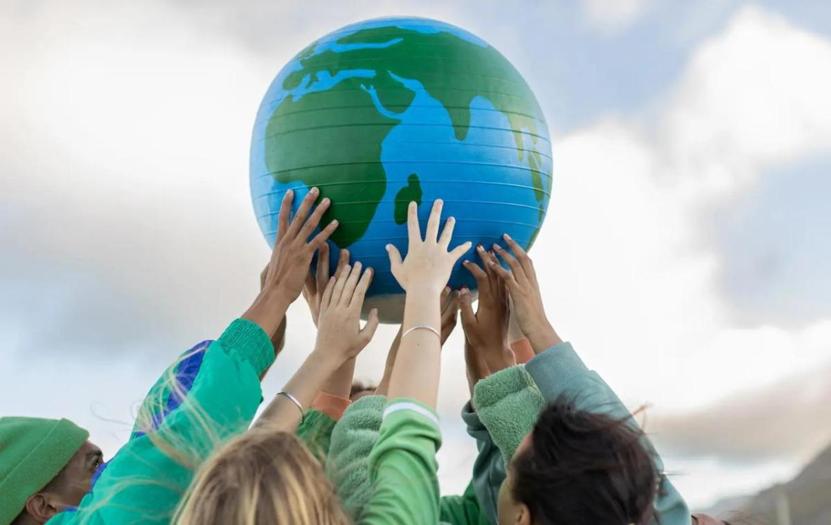 Hands holding up a globe outside