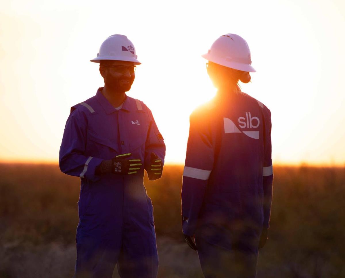 Two SLB workers talking with the sun setting behind them