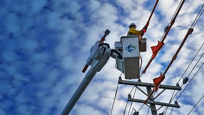 A line worker in a bucket lift working on a power line.