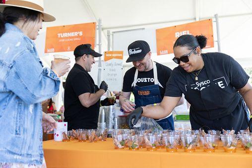 Volunteers pouring drinks on a table with an orange covering