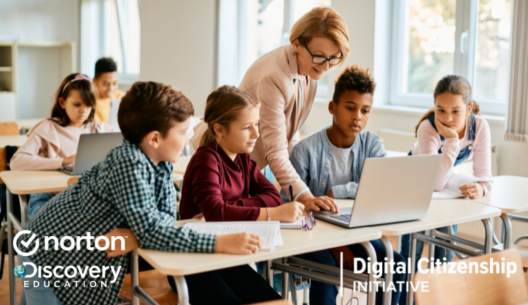 A teacher and young students looking at a laptop in a classroom