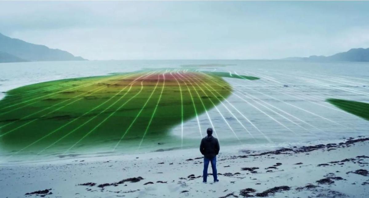 A person on a beach overlooking a body of water. A digital topography overlayed.