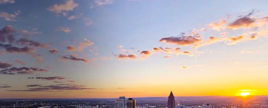 A setting sun in an open sky over a city landscape