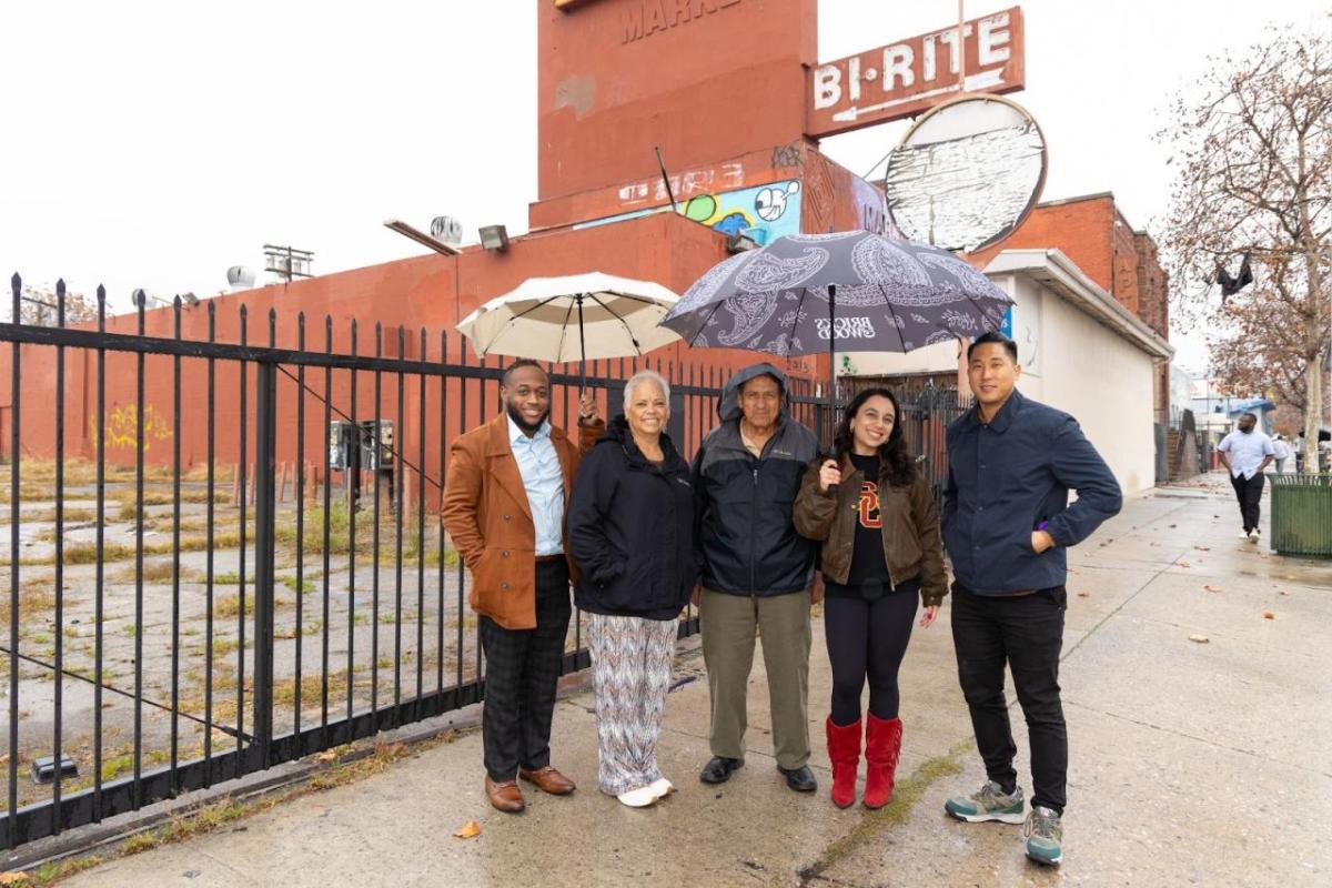 Five people stood together holding umbrellas 