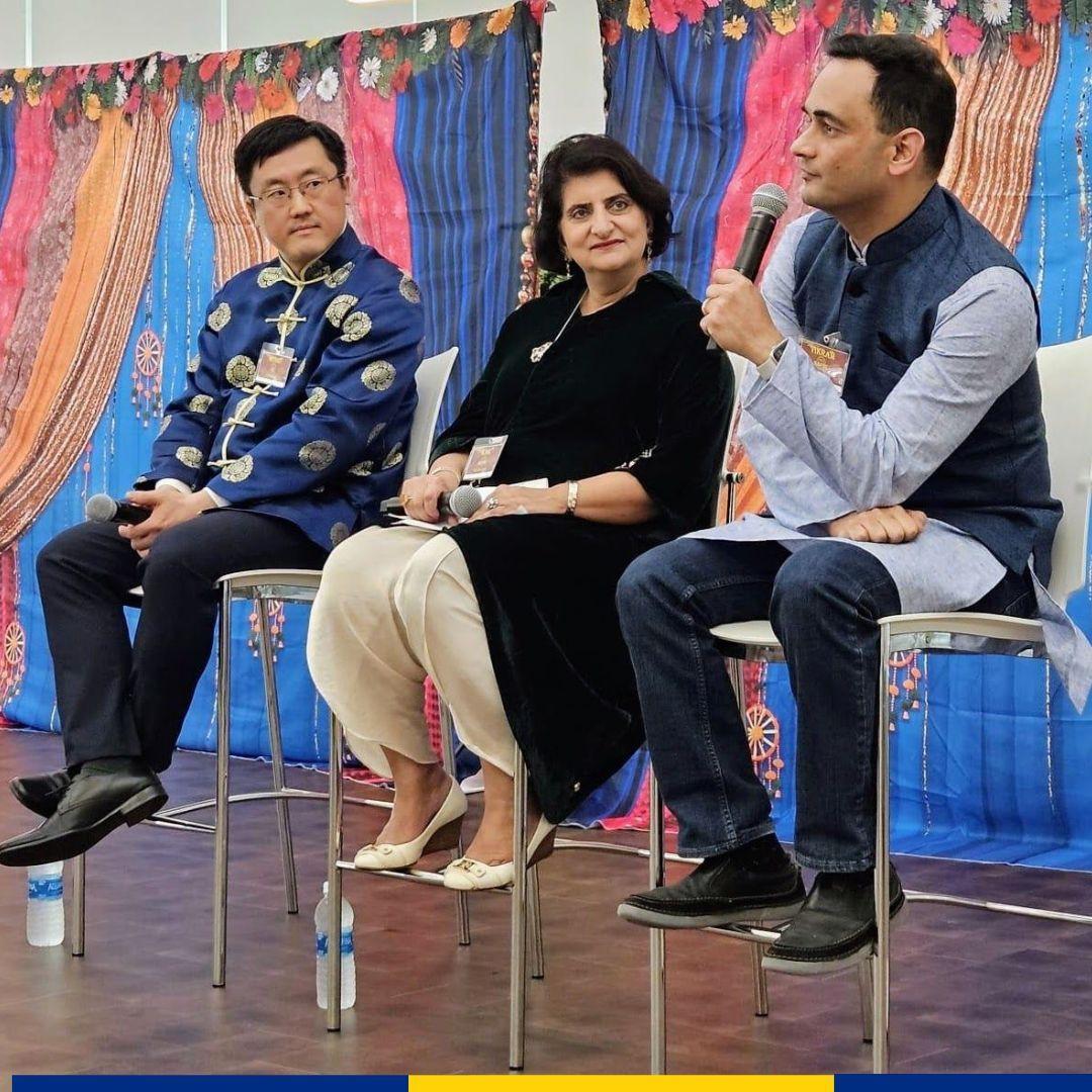 Three seated people on a stage with microphones.