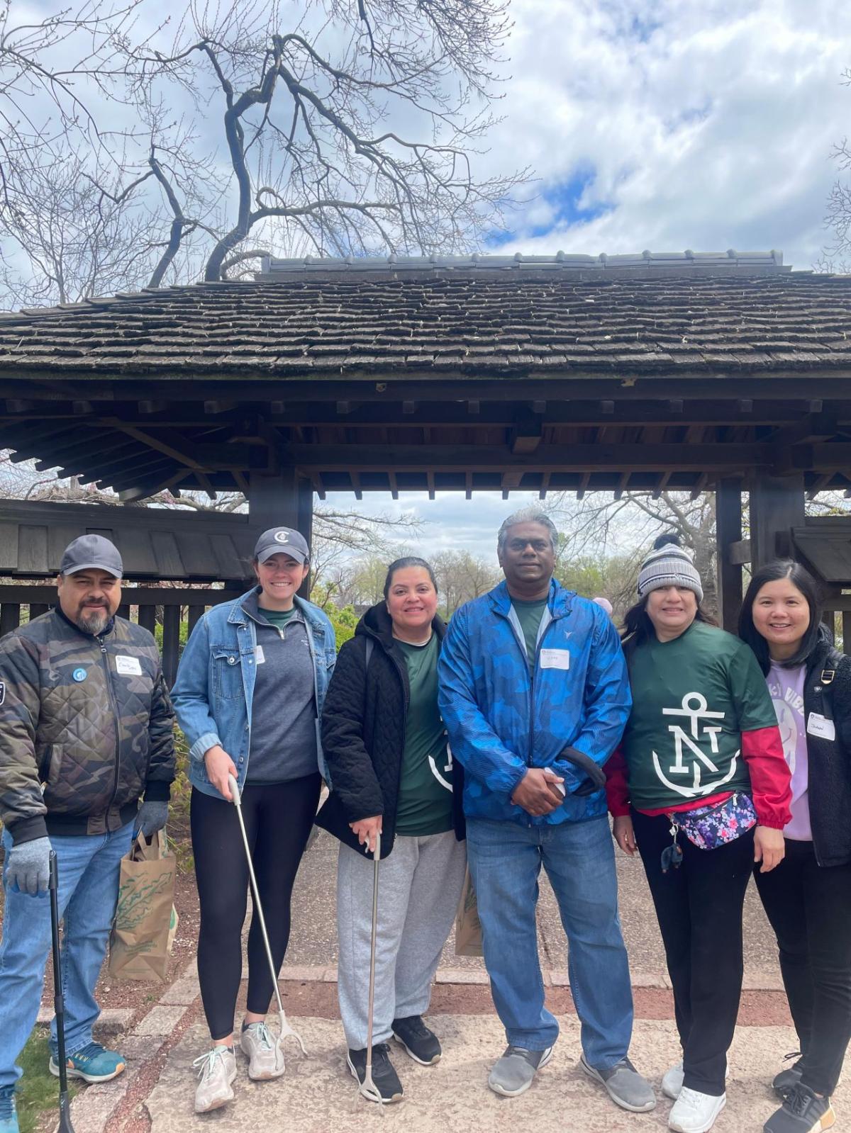 A group posed with trash pickers in a park setting.