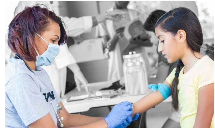 A medical provider cleans the arm of a child in a clinic setting