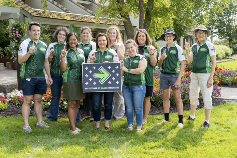 A team posed with a Pelotonia sign, each holding up one finger.