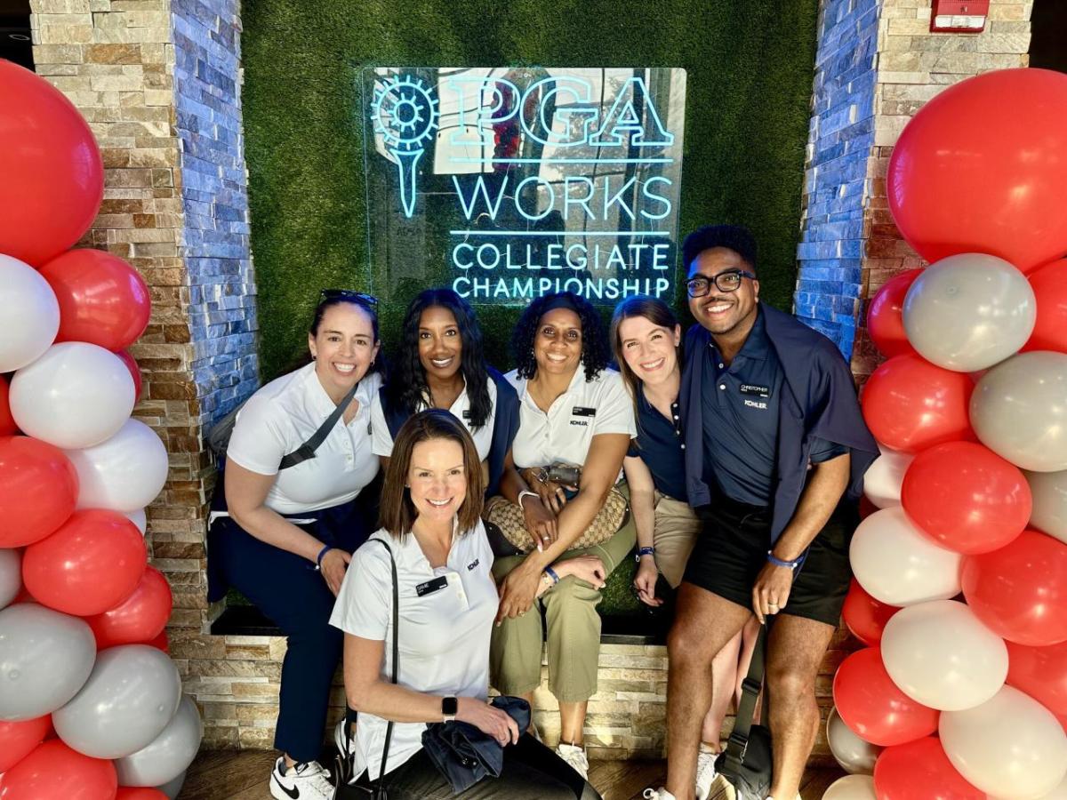 A group posed with balloons in front of a PGA Works sign.