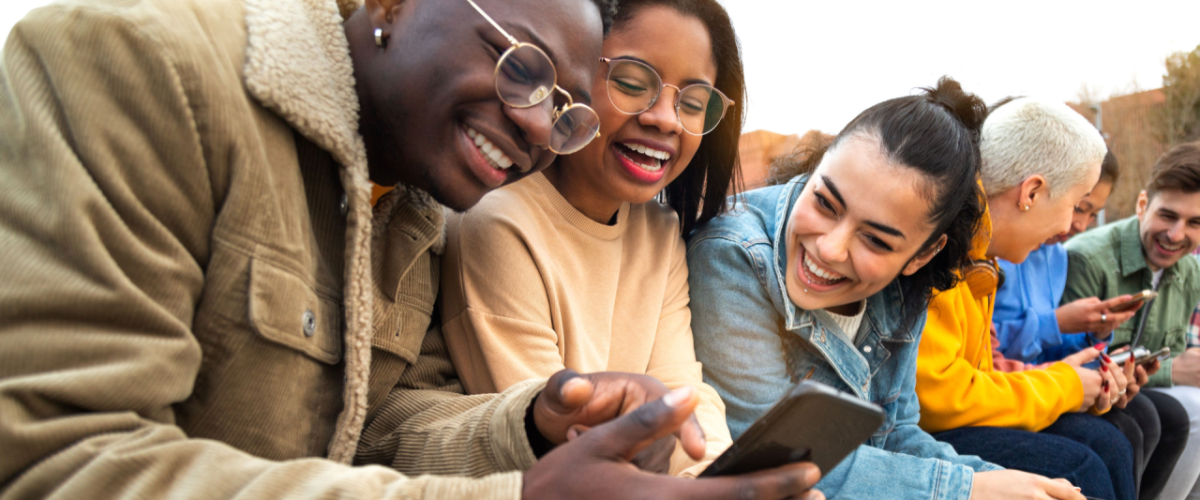 Three people look at a smartphone