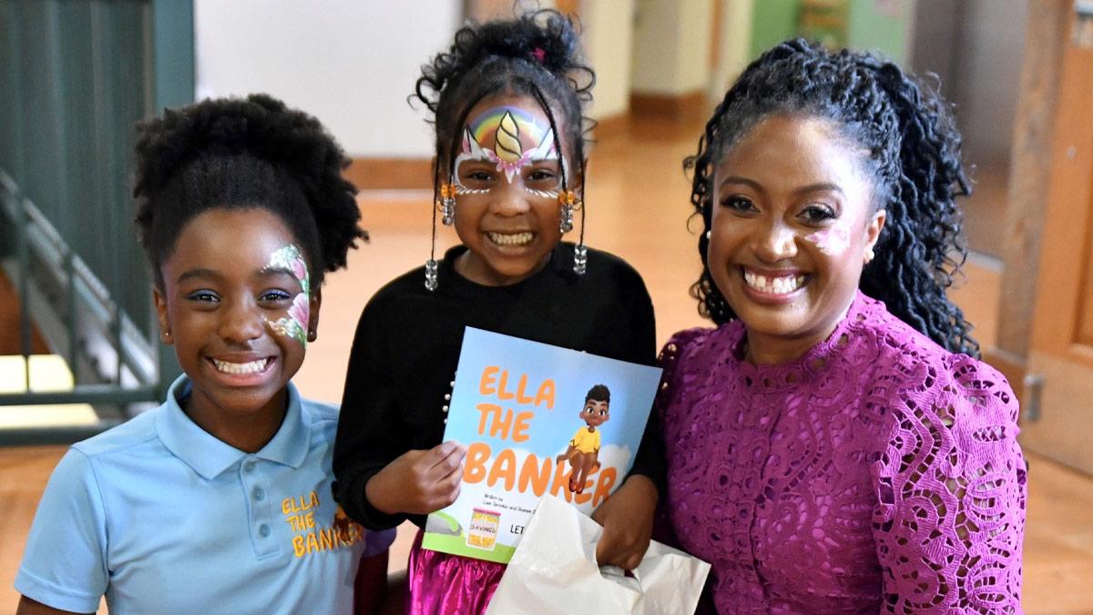 Shamim Okolloh, right, and her daughter, Ella, left, are joined by a young reader holding the book inspired by Ella and written by Ella's brother, Liam.
