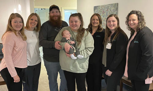 A group of people around a mother and baby