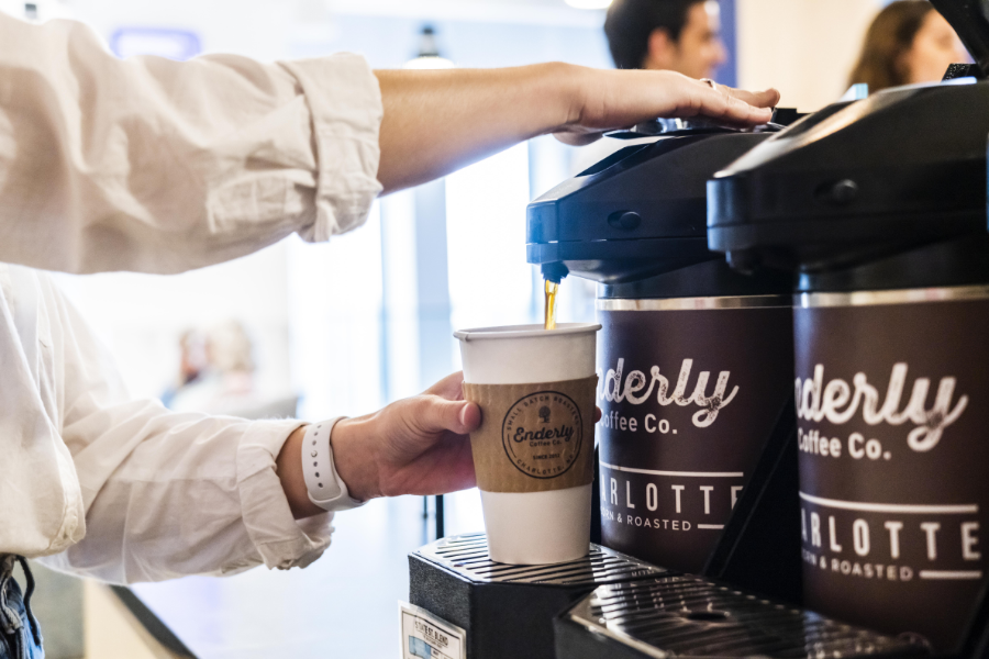 A person getting a cup of coffee from a carafe