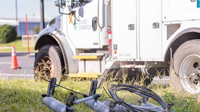 A Duke Energy truck next to power lines/equipment on the ground.