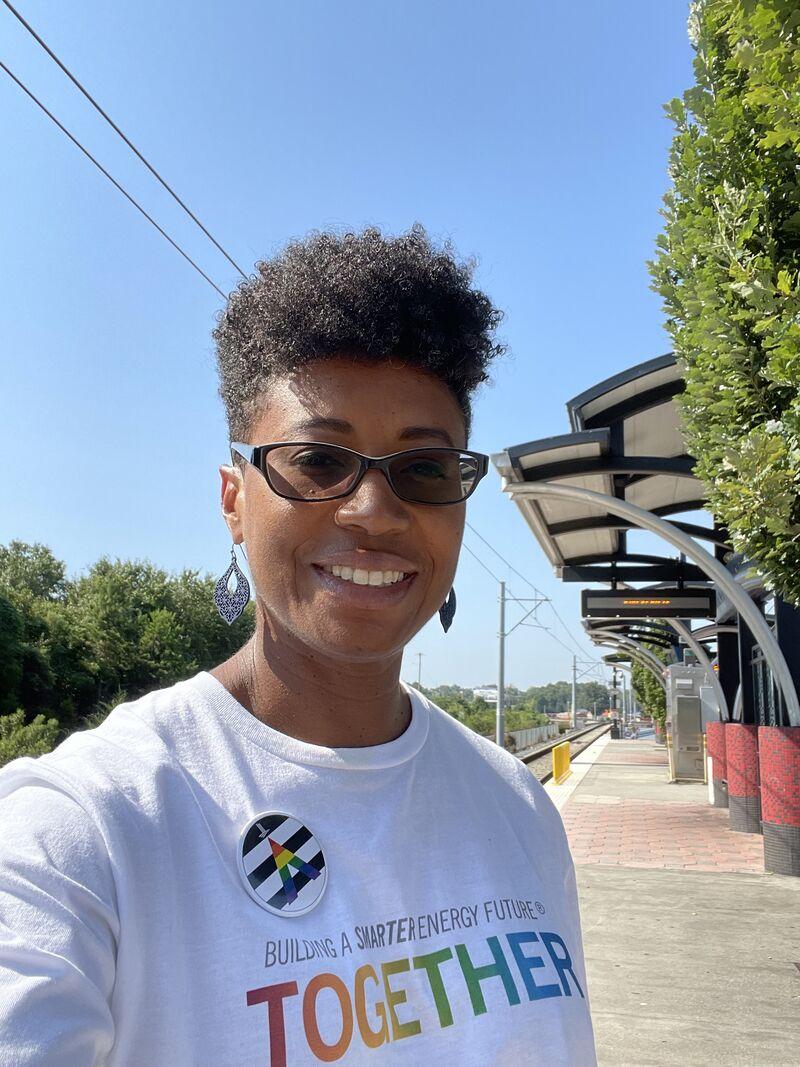 Sharene Pierce on a train platform in a rainbow "Together" shirt.