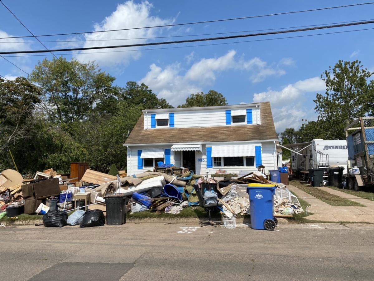 Storm damage to a home, trash from the damage piled up in front of the home.